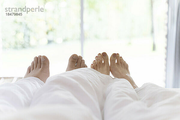 Füße von Mann und Frau unter Decke