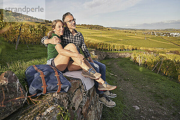 Nachdenkliches älteres Paar sitzt auf einer Mauer im Weinberg