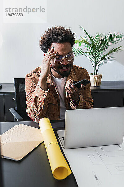 Geschäftsmann benutzt Smartphone am Schreibtisch im Büro