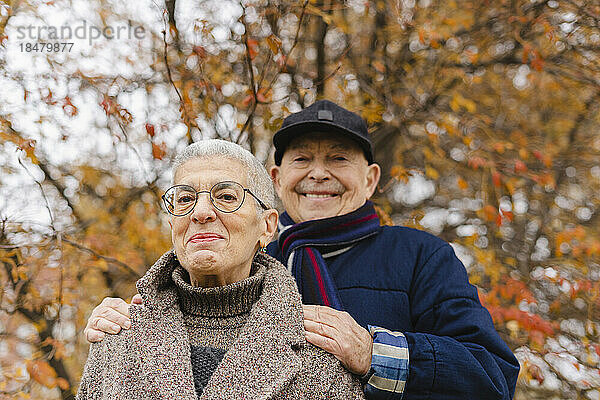 Lächelndes älteres Paar unter Baum im Herbstpark