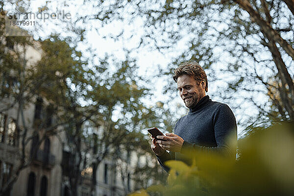 Lächelnder Mann  der sein Mobiltelefon benutzt