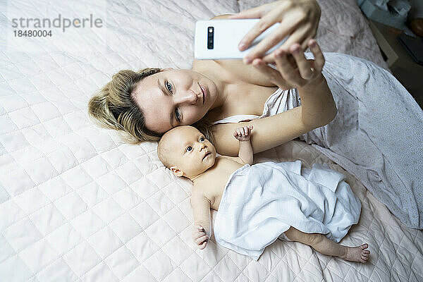 Mutter macht Selfie mit kleinem Jungen per Smartphone zu Hause im Bett