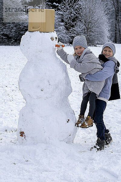 Glücklicher Bruder und Schwester  die Schneemann bauen