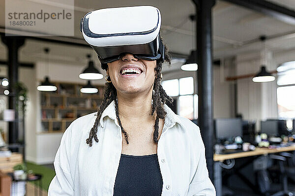 Glückliche Geschäftsfrau mit Virtual-Reality-Simulator im Büro