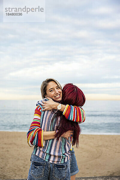 Fröhliche Freunde  die sich am Strand umarmen