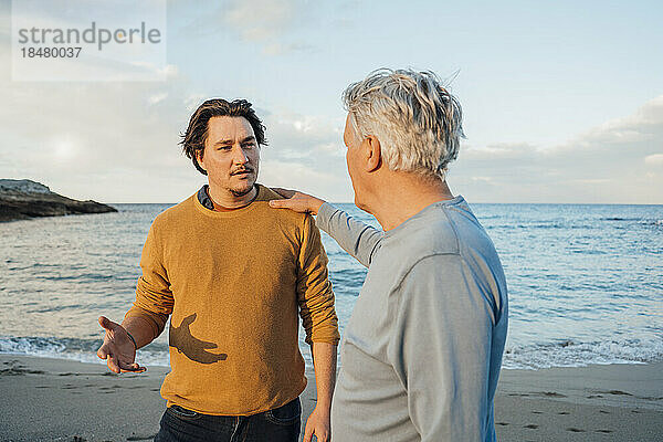Vater und Sohn diskutieren am Strand