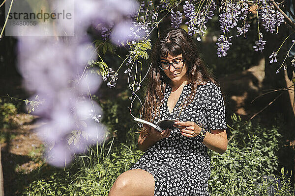 Frau mit Brille liest Buch im Hinterhof