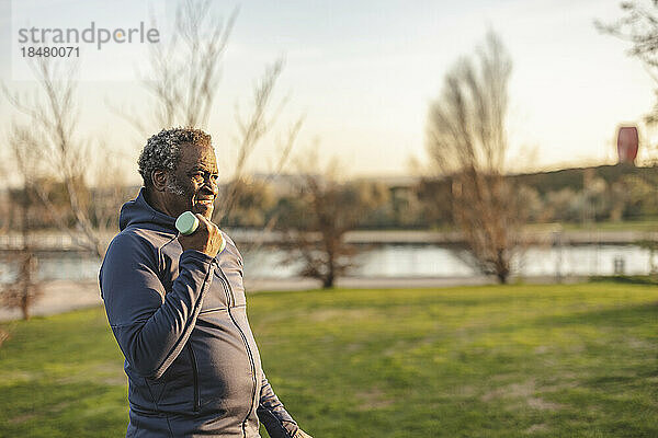 Älterer Mann hält Hantelübungen im Park bei Sonnenuntergang
