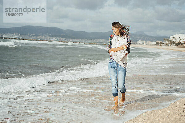 Frau geht am Strand in der Nähe des Meeres spazieren