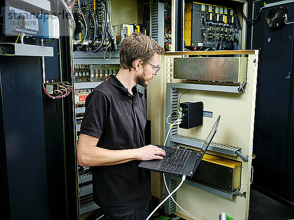 Techniker benutzt Laptop an der Maschine in einer modernen Fabrik