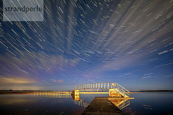 Sternspuren über beleuchtete Brücke bei Nacht