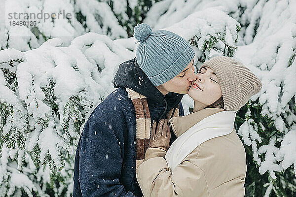 Teenage boy kissing girlfriend at park in winter
