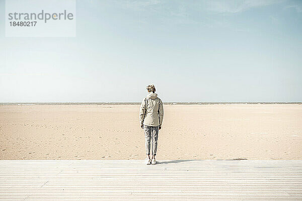 Frau steht auf der Promenade am Strand