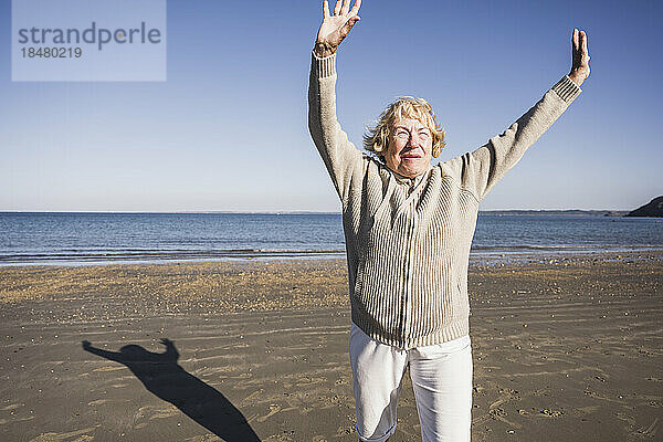 Glückliche Seniorin tanzt im Urlaub am Strand