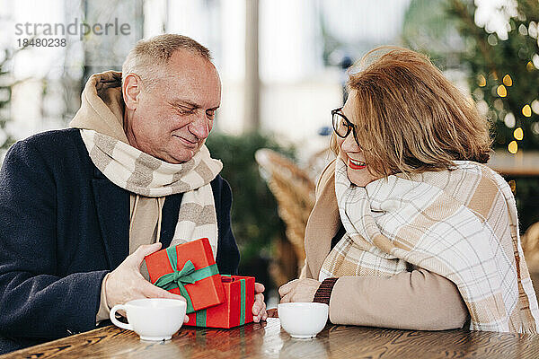 Ältere Frau schenkt älterer Frau im Café ein Geschenk