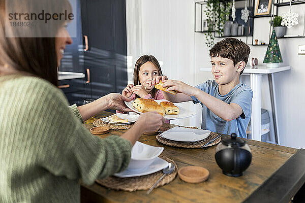 Glückliche Mutter serviert Kindern am Tisch Frühstück