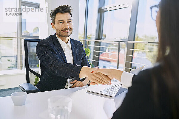 Lächelnder Personalvermittler beim Händeschütteln mit dem Kandidaten im Büro