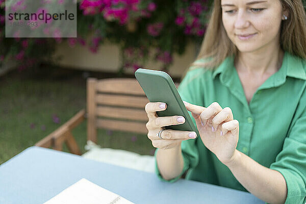 Frau benutzt Smartphone im Garten