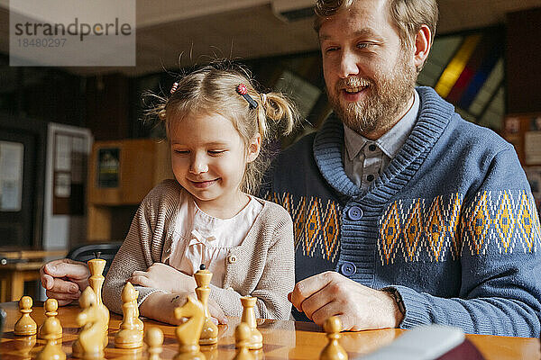 Vater und Tochter spielen Schach im Club
