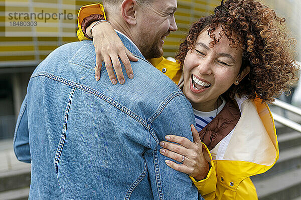 Happy woman with curly hair embracing man