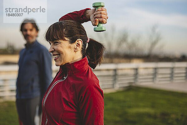 Glückliche reife Frau mit Mann beim Training im Park
