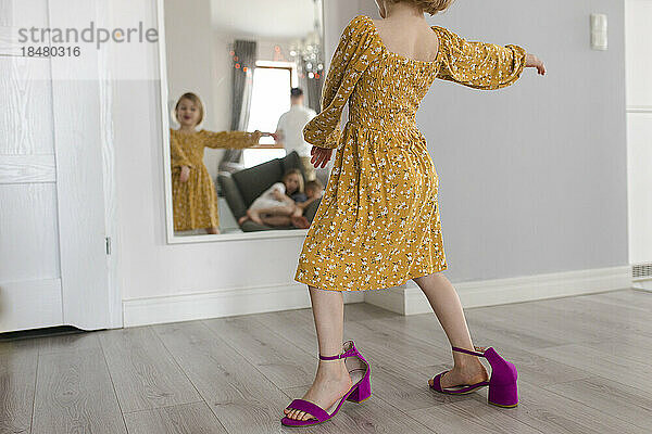 Mädchen in Muttersschuhen tanzt zu Hause vor dem Spiegel