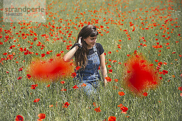 Junge Frau inmitten von Mohnblumen an einem sonnigen Tag