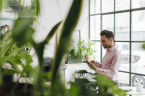 Reifer Geschäftsmann  der im Büro am Tablet-PC arbeitet