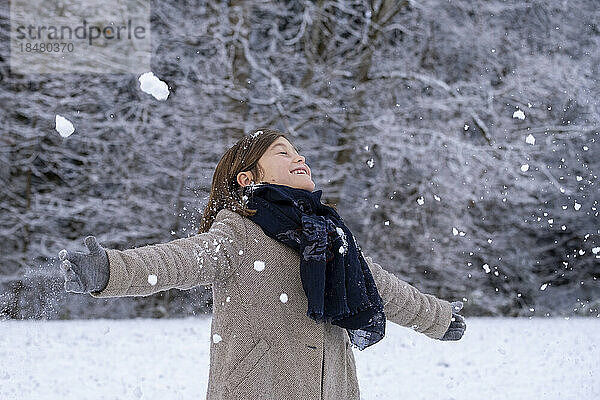 Glückliches Mädchen in warmer Kleidung  das den Schnee genießt