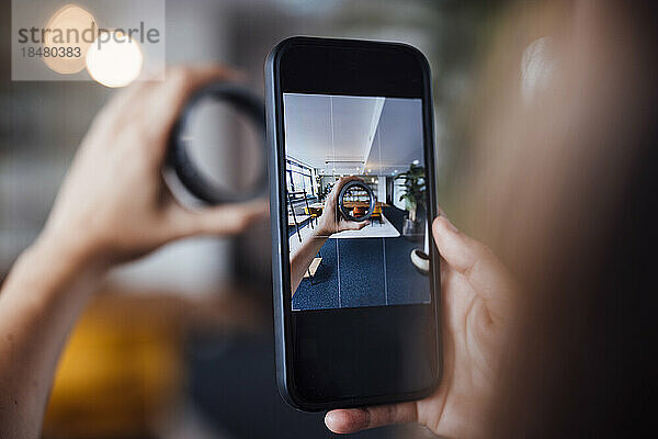 Hände einer Geschäftsfrau  die im Büro kreisförmige Geräte mit dem Smartphone fotografiert