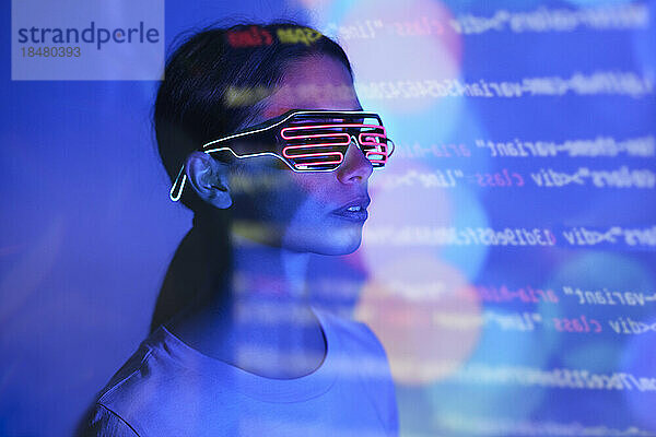 Frau mit futuristischer Brille liest Codes auf leuchtendem Hintergrund