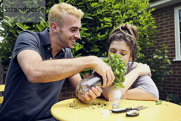 Junger Mann riecht an Pflanze  die sein Freund im Hinterhof hält