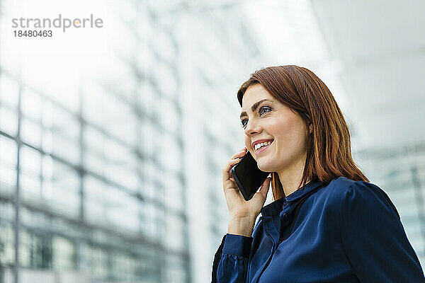 Lächelnde Geschäftsfrau  die am Smartphone spricht