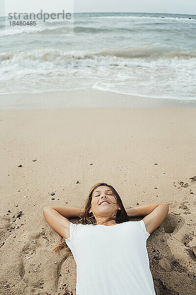 Sorglose Frau entspannt sich in Ufernähe am Strand