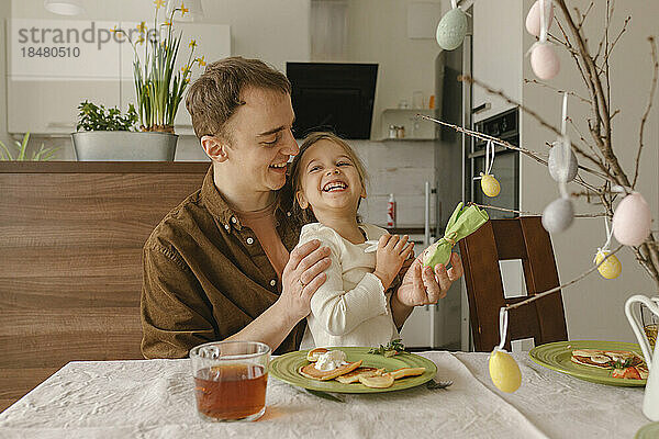 Glücklicher Vater und Tochter mit Osteressen am Tisch