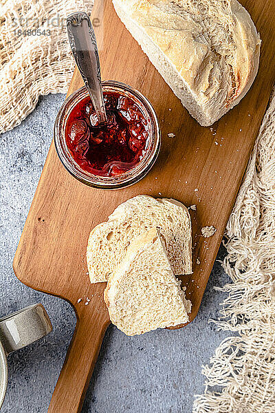 Homemade strawberry jam with bread on cutting board