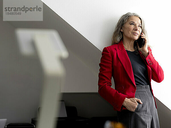 Geschäftsfrau spricht im Büro mit Smartphone