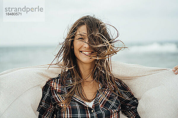 Glückliche Frau mit zerzausten Haaren am Strand