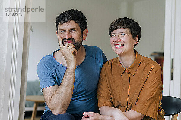 Smiling man with hand on chin by woman at home