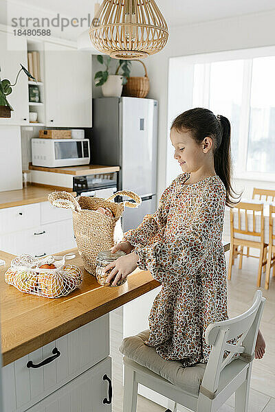 Girl unpacking groceries on kitchen island at home