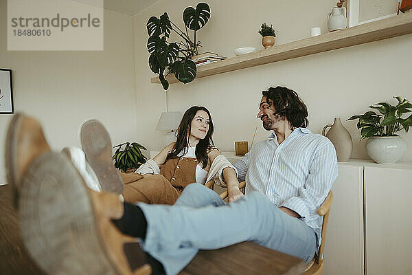 Paar mit erhobenen Füßen sitzt zu Hause