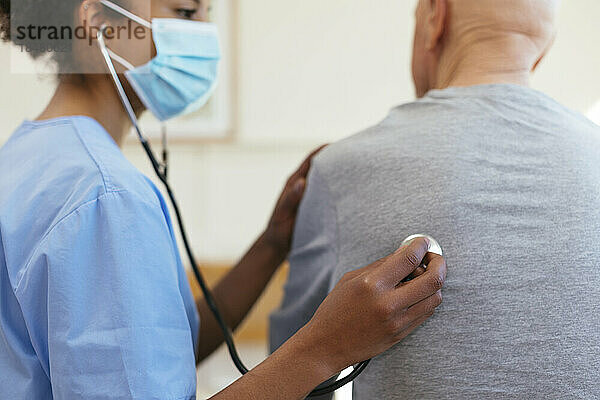 Arzt benutzt Stethoskop  um zu Hause den Herzschlag des Patienten abzuhören