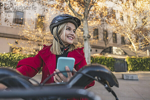 Glückliche reife Frau mit Smartphone und Fahrrad