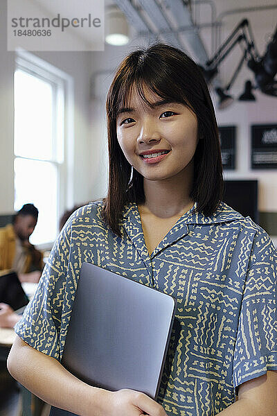Lächelnde Geschäftsfrau mit Laptop am Arbeitsplatz