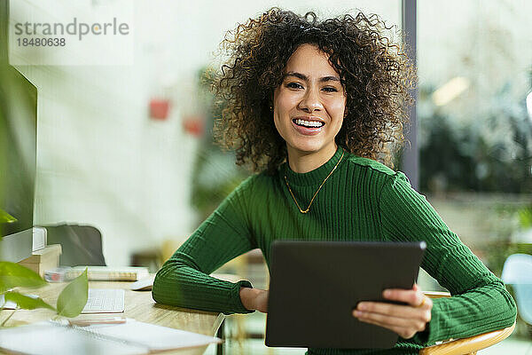 Glückliche Geschäftsfrau mit Tablet-PC am Tisch