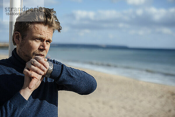 Mann spricht am Strand in eine Smartwatch