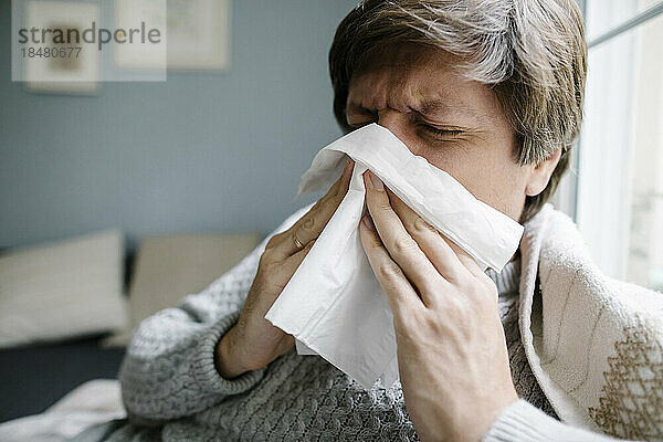 Kranker Mann putzt sich zu Hause die Nase