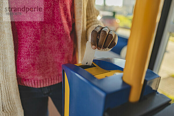 Frau benutzt Fahrkartenautomaten in der Straßenbahn