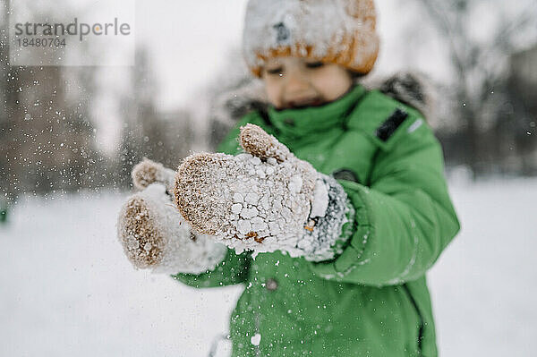 Junge trägt Handschuhe und spielt mit Schnee