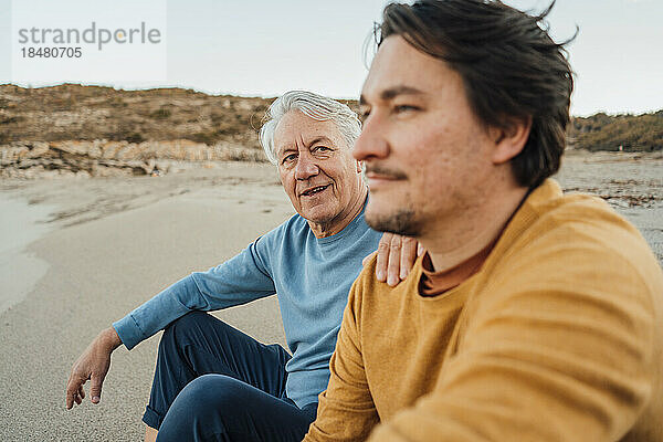 Vater und Sohn diskutieren am Strand bei Sonnenuntergang
